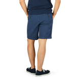 Person standing with hands in pockets, wearing Briglia navy blue cotton linen pleated shorts with an adjustable waistband and sneakers.