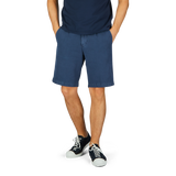 Man standing in a Briglia navy blue cotton linen pleated shorts with an adjustable waistband against a plain background.