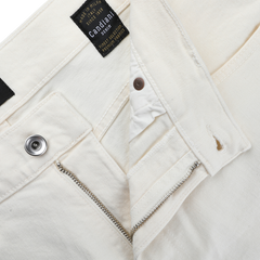 The Ecru Stone Washed Organic Cotton M8 Jeans by C.O.F Studio are made from organic Kuroki Selvedge denim and have a visible metal button and zipper. The inside black label says "Candiani," highlighting their quality craftsmanship.