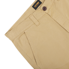 A close-up of Khaki Double Twisted Cotton Twill Fatigue Pants features a buttoned waistband and displays the C.O.F Studio brand label on the inside. Made from recycled fibers, the fabric looks smooth and well-tailored.