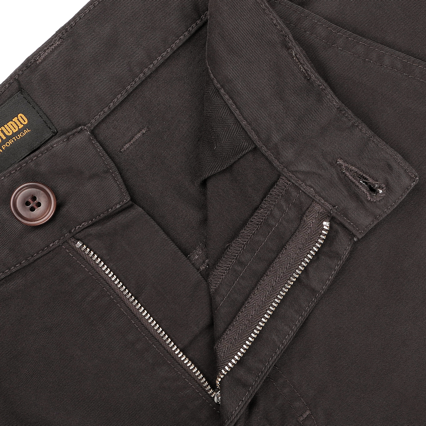 Close-up of the Liquorice Double Twisted Cotton Twill Fatigue Pants by C.O.F Studio in a dark brown hue, complete with a button, zipper, and an inside label that reads "MADE IN PORTUGAL".