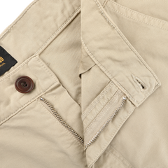 Close-up of C.O.F Studio's Sand Double Twisted Cotton Twill Fatigue Pants made from recycled fibers, showcasing a brown button, partially open zipper, belt loops, and stitching detail.