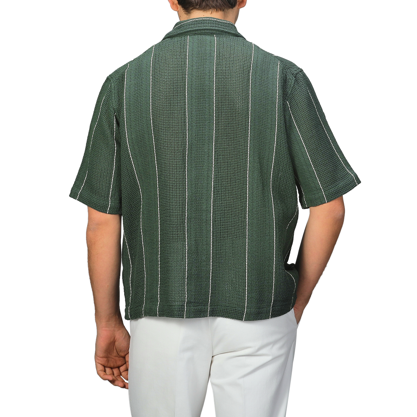 A person is seen from the back wearing a C.O.F Studio Dark Green Striped Crochet Relaxed Camp Shirt with white pants.