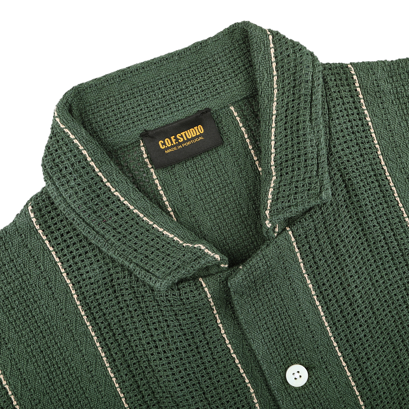 The Dark Green Striped Crochet Relaxed Camp Shirt by C.O.F Studio is made from pure cotton mesh, featuring a camp collar with buttons and white vertical stripes, offering comfort and style. A label inside reads "C.O.F. Studio Made in Portugal.