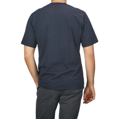 A person is standing with their back to the camera, wearing a C.O.F Studio Navy Blue Organic Cotton Crewneck T-Shirt and dark pants.