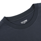 Close-up of the Navy Blue Organic Cotton Crewneck T-Shirt by C.O.F Studio, showcasing a label that reads "C.O.F. STUDIO 100% ORGANIC COTTON." The regular fit neckline and part of the shoulder area are visible.