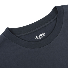 Close-up of the Navy Blue Organic Cotton Crewneck T-Shirt by C.O.F Studio, showcasing a label that reads "C.O.F. STUDIO 100% ORGANIC COTTON." The regular fit neckline and part of the shoulder area are visible.