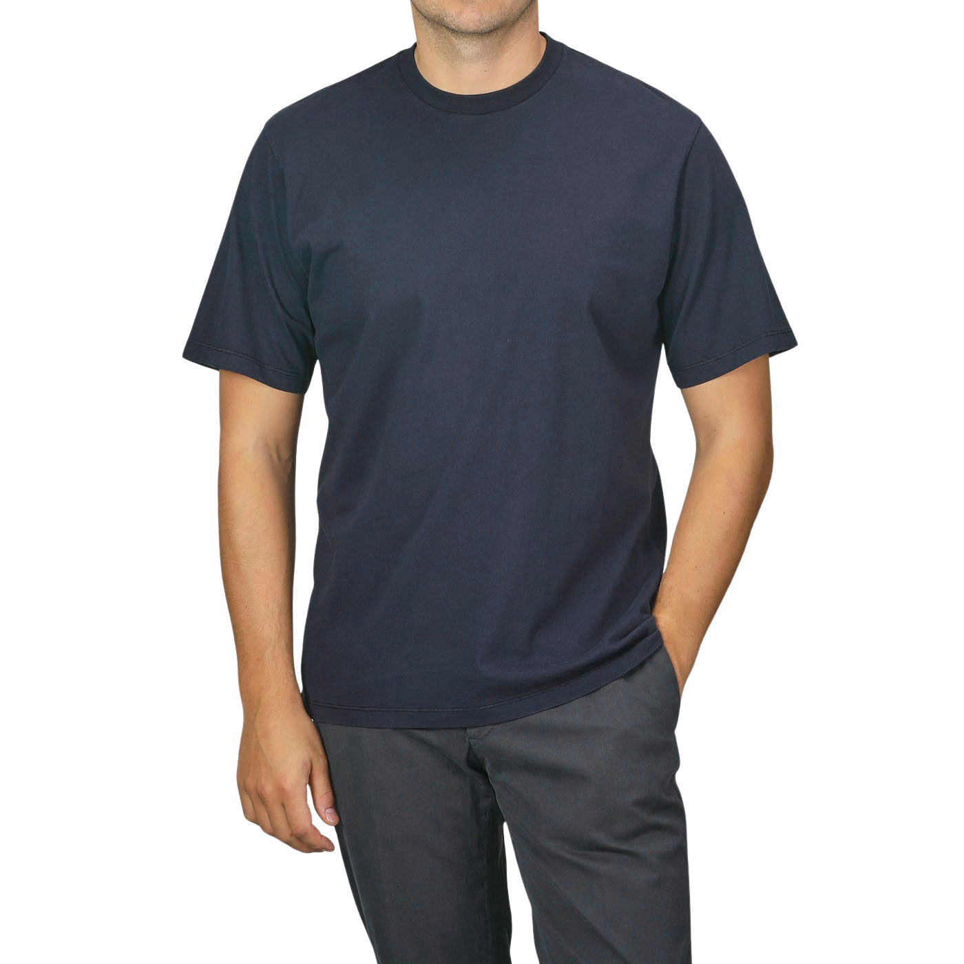 A person wearing a Navy Blue Organic Cotton Crewneck T-Shirt from C.O.F Studio and dark pants stands with one hand in their pocket against a plain background.