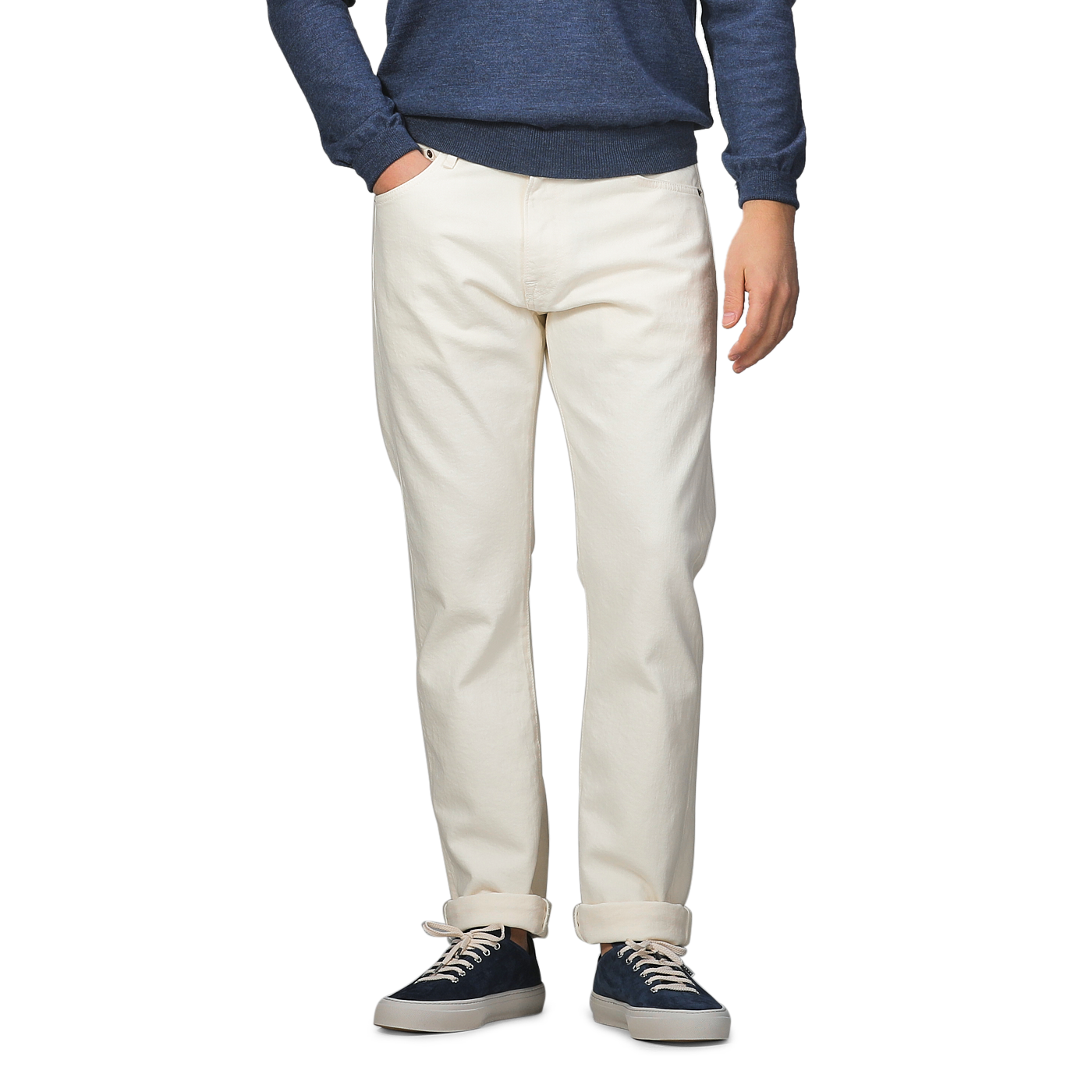 A person dressed in a blue sweater, Ecru Stone Washed Organic Cotton M8 Jeans from C.O.F Studio, and navy sneakers stands against a neutral background.