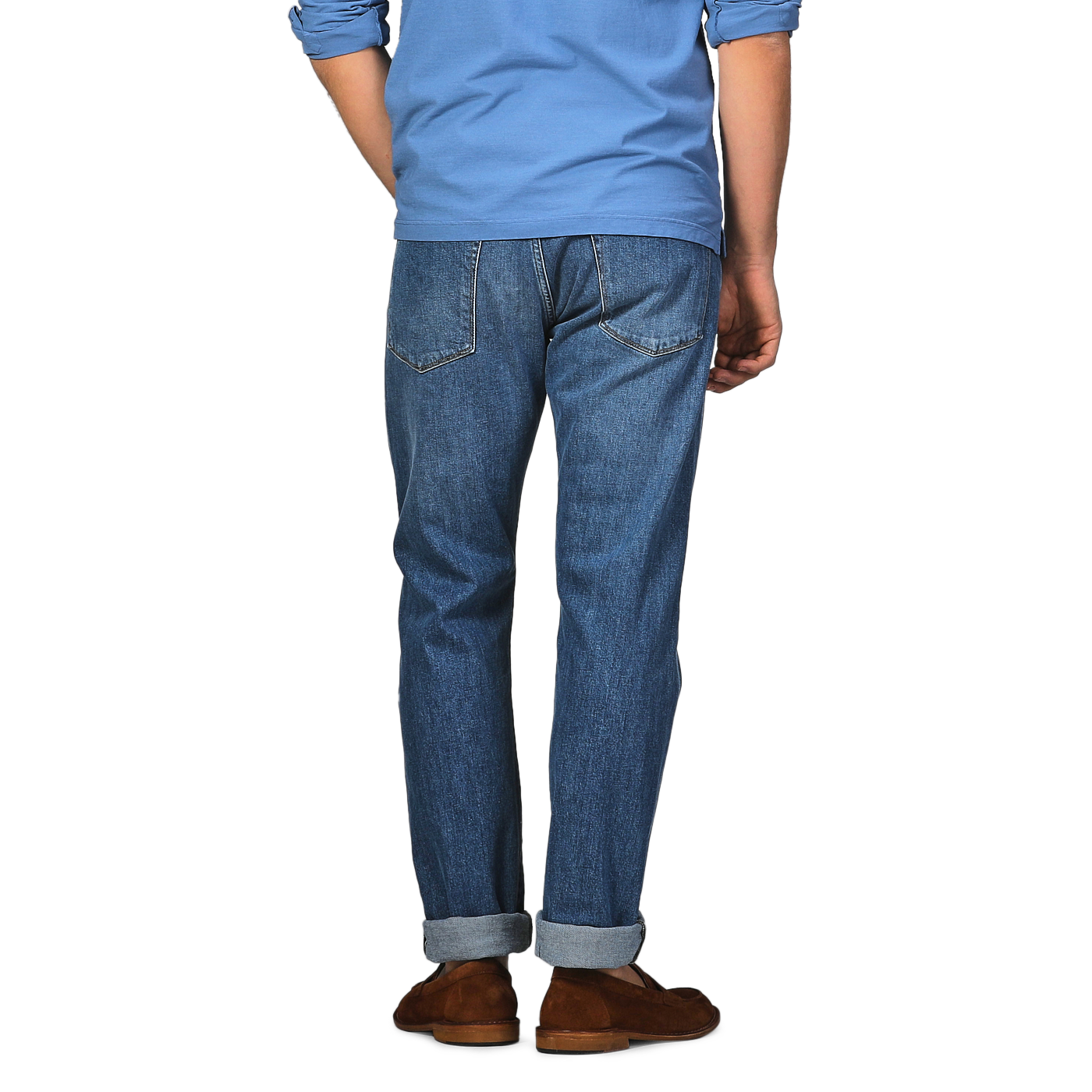 Rear view of a person in a blue shirt and brown shoes, standing with arms relaxed, showcasing C.O.F Studio's Indigo Blue Washed Organic Cotton M8 Jeans made from organic Kuroki Selvedge denim.