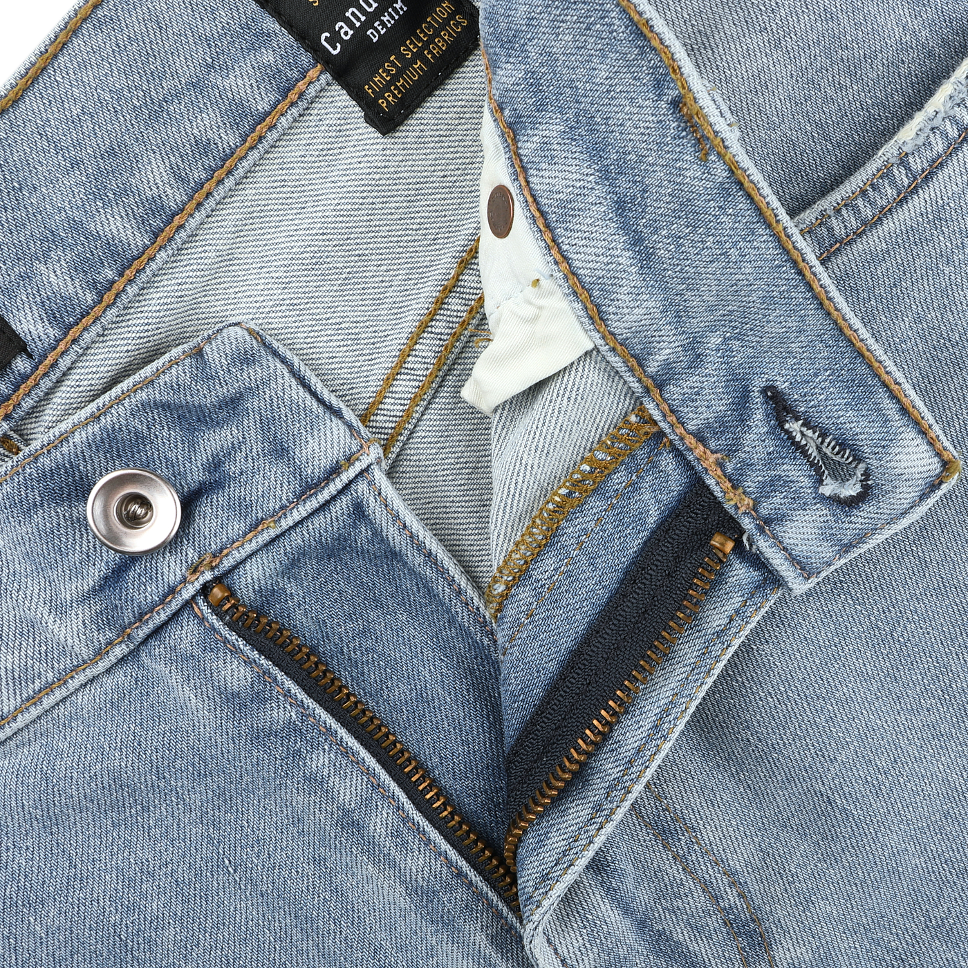 Close-up of washed light blue jeans branded as C.O.F Studio's Light Blue 90's Wash Organic Cotton M8 Jeans, featuring a button and zipper, partially opened to reveal inner stitching and label.