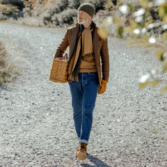 A man in Blue Organic Kurioki Cotton M7 6x Wash jeans made by C.O.F Studio walking down a dirt road with a basket made of organic cotton.