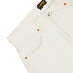 Close-up of white, organic Ecru Stone Washed Kuroki Cotton M5 jeans featuring a pocket and copper rivets, with a black 'C.O.F Studio' brand label visible.