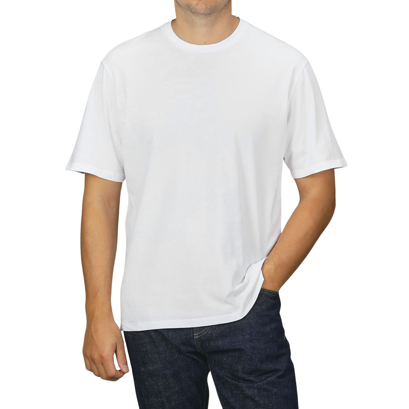 A person dressed in a C.O.F Studio White Organic Cotton Crewneck T-shirt and dark jeans, standing against a neutral grey background with one hand in their pocket.