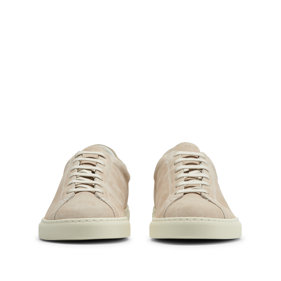 A pair of Beige Suede Leather Racquet Sneakers from CQP, with white laces and a Margom rubber sole, displayed facing forward on a transparent background.