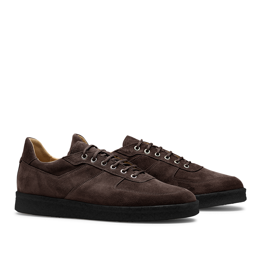 A pair of CQP Chocolate Brown Roamer Sneakers, featuring handcrafted suede leather with black rubber soles and white laces, shown from a side angle.