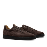 A pair of CQP Chocolate Brown Roamer Sneakers, featuring handcrafted suede leather with black rubber soles and white laces, shown from a side angle.