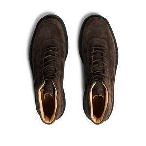 A pair of Dark Brown Suede Leather Sabulo Boots with a water-repellant suede upper, viewed from above on a striped black background by CQP.