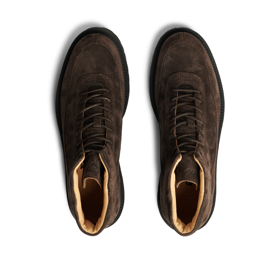 A pair of Dark Brown Suede Leather Sabulo Boots with a water-repellant suede upper, viewed from above on a striped black background by CQP.