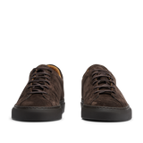 The CQP Ebony Brown Racquet Sr sneakers, made from dark brown suede calf leather with black outsoles, are viewed from the front and provide improved arch support for exceptional comfort.