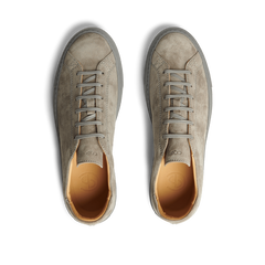 A pair of Granit Grey Suede Leather Racquet Sr sneakers by CQP with laces, viewed from above on a striped black and white background.