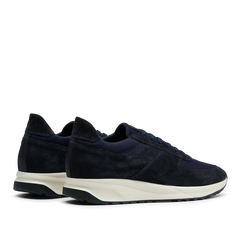 A pair of Obsidian Blue Suede Leather Stride Runners by CQP, with white Gommus soles, displayed side by side on a transparent background.