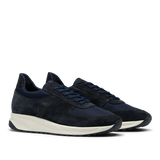 A pair of Obsidian Blue Suede Leather Stride Runners with a white Gommus sole, made of suede and mesh material, displayed against a translucent background by CQP.