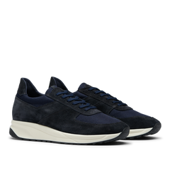 A pair of Obsidian Blue Suede Leather Stride Runners with a white Gommus sole, made of suede and mesh material, displayed against a translucent background by CQP.