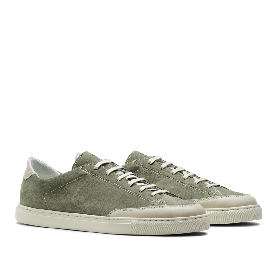 The Olive Green Suede Leather Bumper Sneakers by CQP capture the retro tennis shoe aesthetic with crisp white laces and durable white rubber soles for a classic yet stylish look.