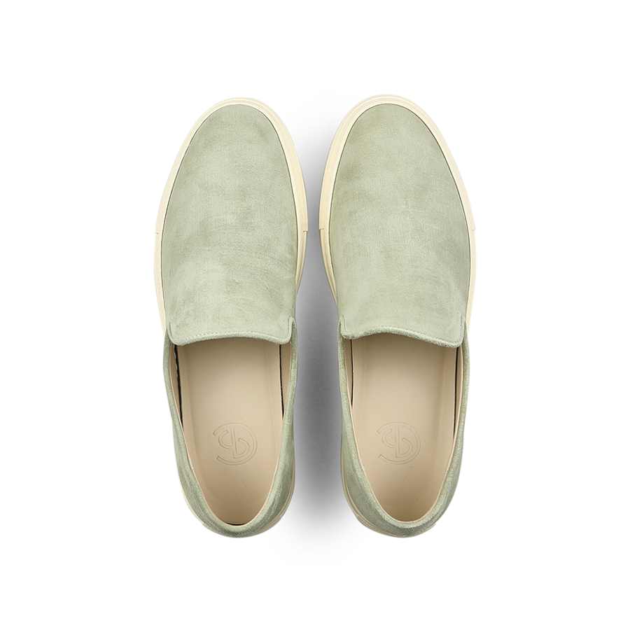 The Sage Green Textured Suede Jetty Wholecut Slip-On by CQP is a stylish, slipper-like shoe featuring light tan supportive rubber soles, viewed from above.