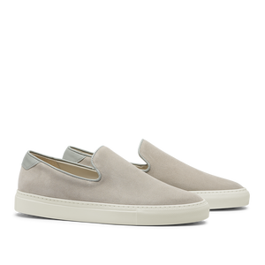 A pair of light beige Sand Suede Jetty Wholecut Slip-on sneakers with white rubber soles on a transparent background by CQP.
