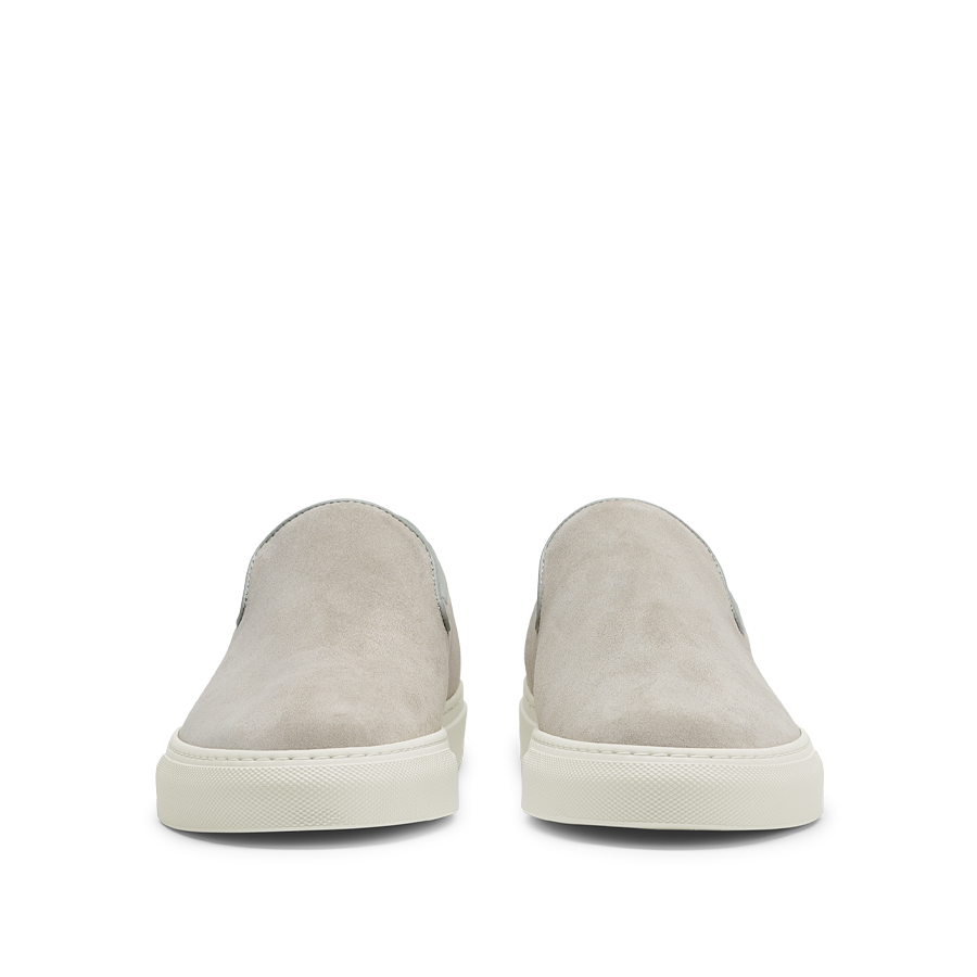 A pair of Sand Suede Leather Jetty Wholecut Slip-on shoes with white rubber soles, handmade in Portugal by CQP, displayed on a translucent background.