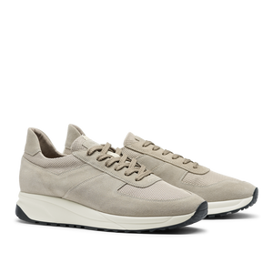 A pair of Tahini Beige Suede Leather Stride sneakers by CQP with laces, featuring suede and fabric materials on a white sole, displayed against a transparent background.