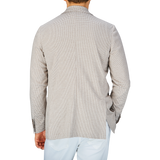 Rear view of a person wearing a Canali Beige Houndstooth Cotton Jersey Blazer with the collar turned up.