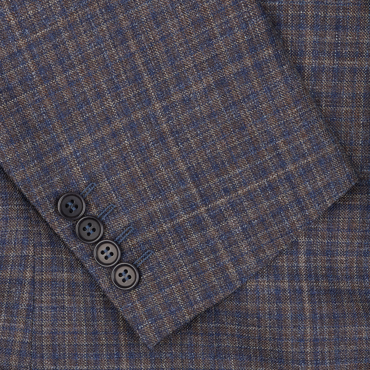 Close-up of a blue gingham checked Canali blazer fabric with a visible folded edge and four black buttons.