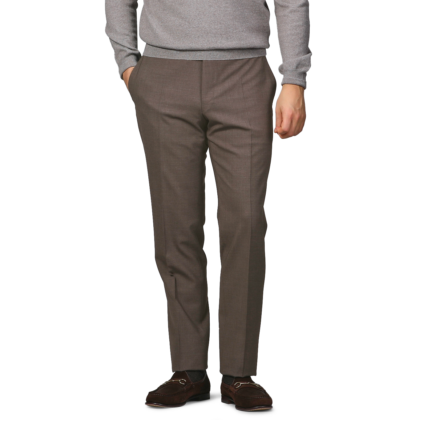 Wearing Canali's Brown Matte Wool Flat Front Trousers, a gray sweater, and brown loafers, a person poses with one hand in their pocket against a light gray backdrop.