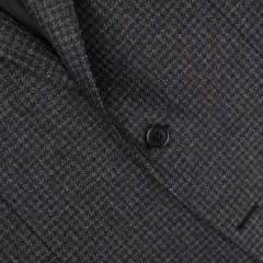 Close-up of a dark blue, checked wool blazer by Canali, featuring a single black button fastened and showcasing its full canvas construction and pure wool elegance.