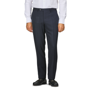 A person in a white shirt, Canali Dark Blue Melange Wool Flat Front Trousers with customizable length, and black loafers stands against a plain background.