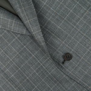 Close-up of a Canali green checked wool silk linen blazer with a focus on a button, showcasing the texture and pattern of the material.