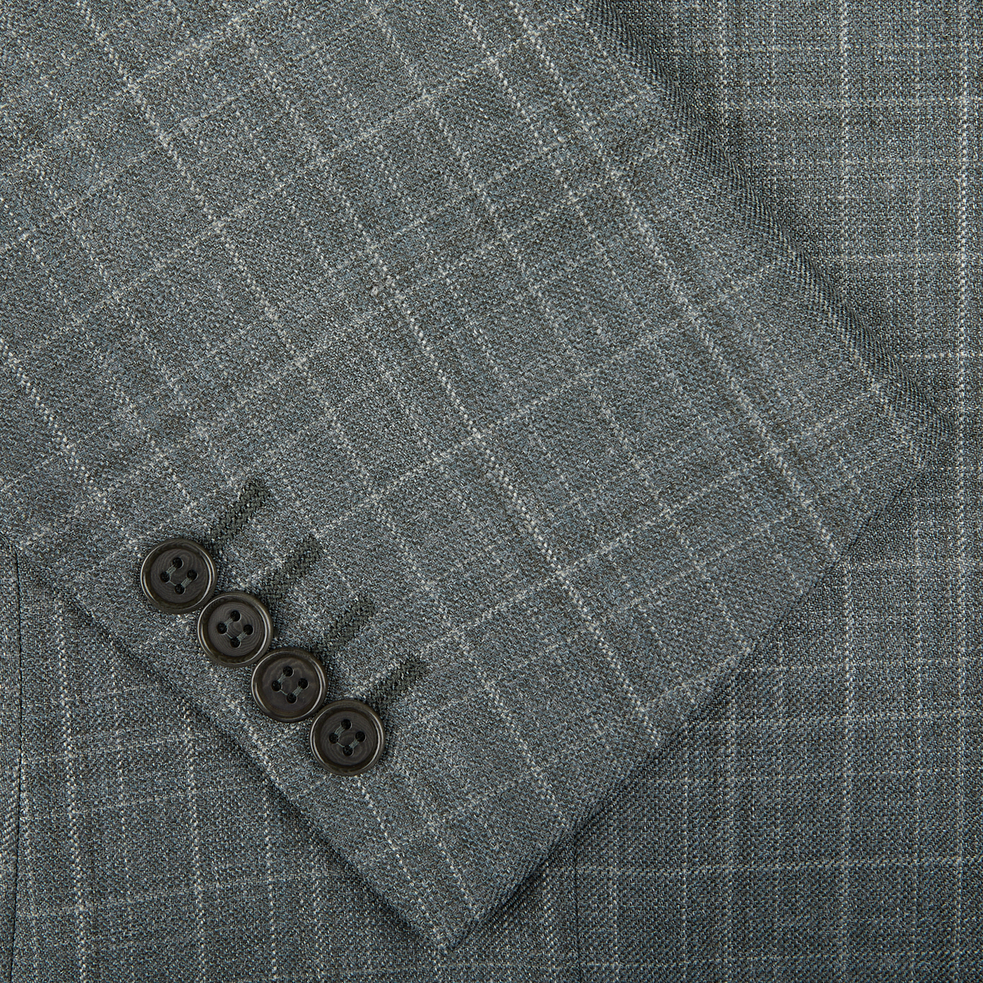 Close-up of a Canali green checked wool silk linen blazer fabric with a focus on three dark buttons, showcasing the texture and pattern of the material.