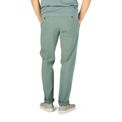 The man is wearing sage green cotton stretch flat front chinos from Canali.