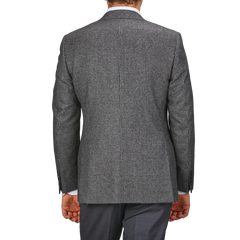 A person clad in the Grey Dogtooth Wool Drop 6 Blazer from Canali and matching gray pants, tailored from pure wool, is captured from the back with their arms hanging by their sides.