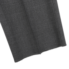 Close-up of a folded piece of textured dark gray fabric with a frayed edge, reminiscent of the refined elegance found in Canali's Grey Melange Wool Flat Front Trousers, ideal for tailored formal wear.