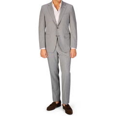 A man in a Canali Light Grey Micro Check Wool Suit and brown shoes standing against a white background.