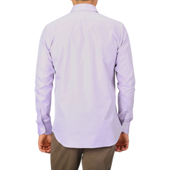 A man wearing a Canali Lilac Cotton Herringbone Single Cuff Shirt and brown pants stands with his back facing the camera.