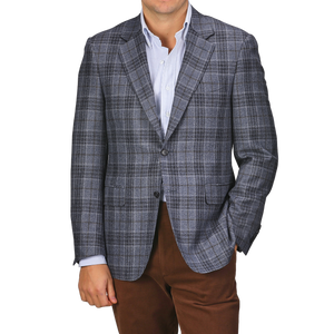 A person dressed in the sophisticated Mid Blue Checked Wool Silk Drop 6 Blazer by Canali, stylishly paired with a light blue shirt and brown pants.