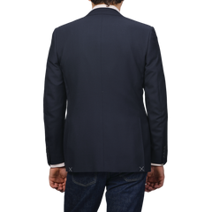 Rear view of a person in a Canali Navy Blue Hopsack Wool Blazer paired with jeans against a gray background.