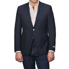 A person dons the Canali Navy Blue Hopsack Wool Blazer, paired with a light striped shirt and blue jeans. The blazer, stylishly detailed with pockets and buttons, captures a refined Milanese essence.