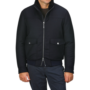 A person wearing the Canali Navy Blue Wool Bomber Jacket, featuring a detachable beaver fur collar, along with dark pants stands against a plain background.