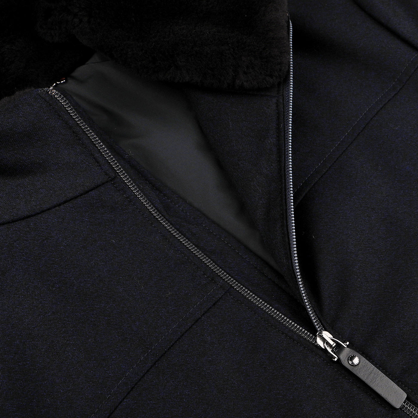 Close-up of a navy blue wool bomber jacket with a partially open zipper, revealing a soft black inner lining and featuring a detachable beaver fur collar by Canali.